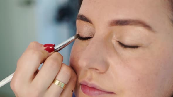 Women Do Makeup Paint the Eyelids on the Eyes with a Makeup Brush