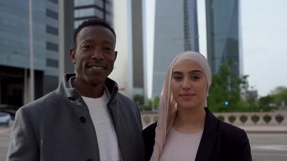 Multiracial business people looking on camera with city tower in the background