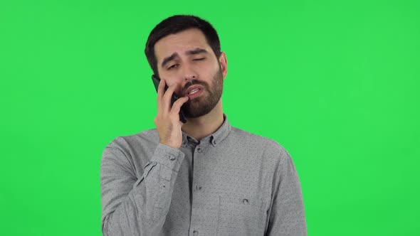 Portrait of Brunette Guy Is Angrily Talking for Mobile Phone. Green Screen