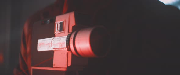 Close up of man in red lights holding vintage camera