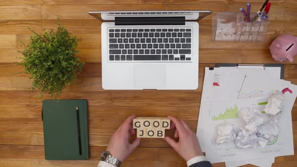 Phrase is a good job done by hands from wooden cubes on the desktop. On table put cubes with the wor