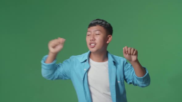 The Smiling Young Asian Boy Dancing In A Green Screen Studio