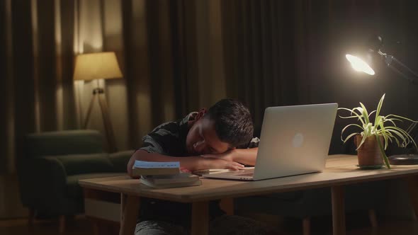 Tired Teenage Boy Sleeping On The Table At Home After Doing Home Work At Night Time