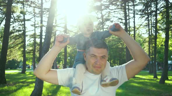 Baby Sitting on Shoulders of Father During Family Walk in Nature