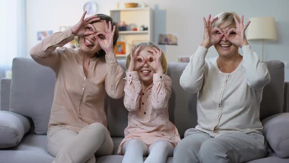 Child With Mother and Granny Making Funny Faces, Gesturing Goggles by Hands, Fun