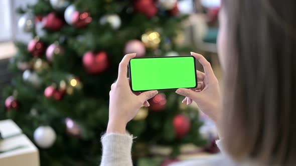 Woman Holding Chroma Key Screen Smartphone Near Christmas Tree