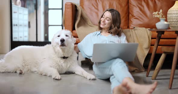 Woman with a Dog and Laptop at Home
