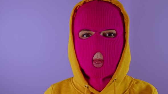 Close Up of Unrecognizable Woman in Pink Balaclava Shows Her Tongue on Purple Background