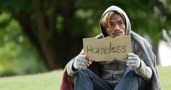Homeless man sitting and holding homeless sign