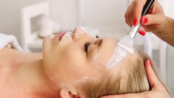 Beautician cosmetologist cleans removes face peeling beauty mask.