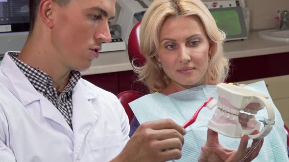 Male Dentist Showing His Patient How To Brush Teeth on a Jaw Mold