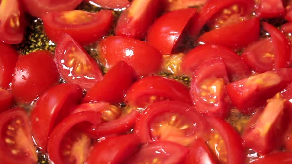 Cooking tomatoes in oil in a pan. Healthy vegetarian vegan organic food close up. Slider shot.