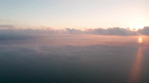 Aerial video over а morning calm sea and beautiful sunrise with low clouds