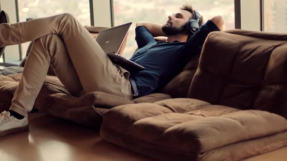 Man Relaxing In Office.Businessman Listening Music On Workplace.Comfortable Sofa In Office.Lazy Time