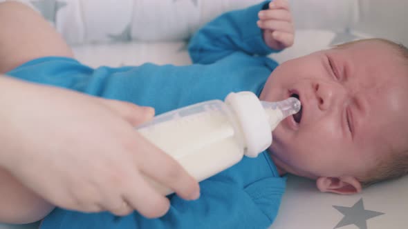 Mommy Feeds Little Child with Milk Mix in Comfortable Cocoon