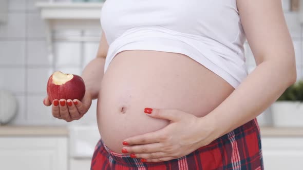 Closeup Belly of a Pregnant Woman with Red Apple