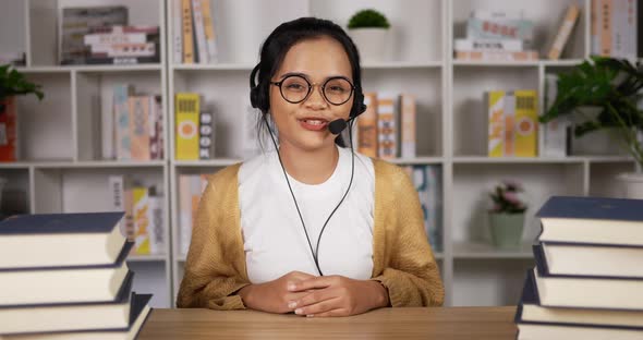 Happy female student in headphones and glasses talking at camera