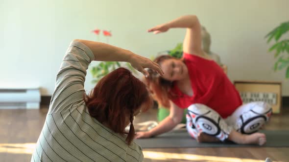 Woman Following Trainer Doing Side Bend Yoga
