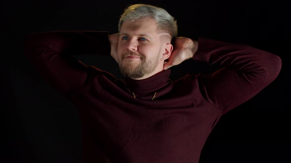 Smiling Cheerful Young Man Holding Hands Crossed Over Head Looking at Camera Black Background