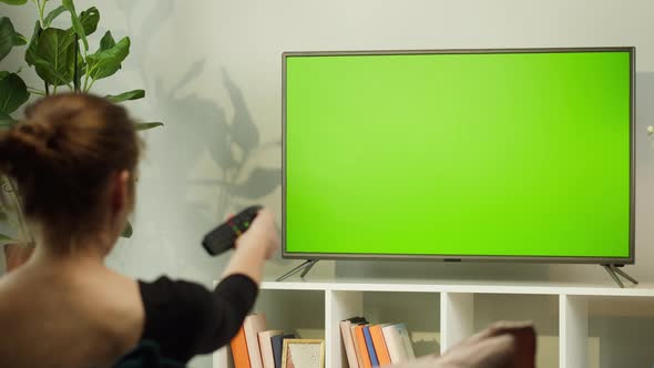 Woman Watching TV with Green Screen in Living Room Back View