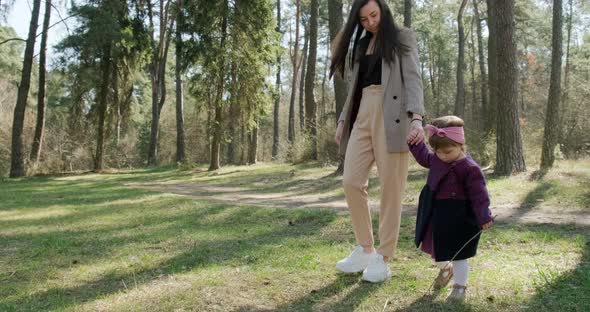 Happy Little Girl Walking and Playing with Mother Among Trees in Coniferous Forest, Healthy Child