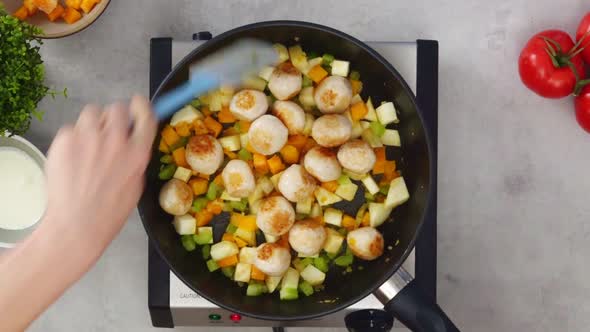 Crop person adding meatballs to stew