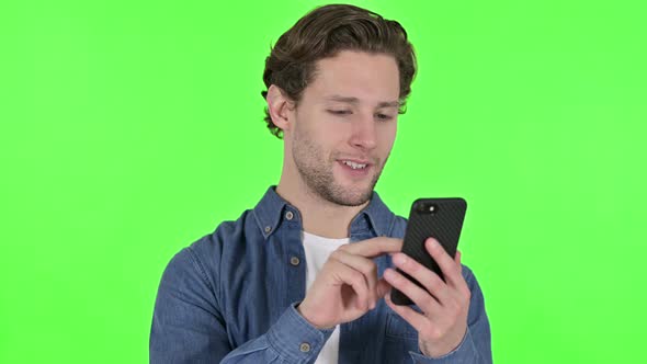 Portrait of Young Man Using Smartphone on Green Chroma Key