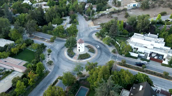 Aerial orbit of Leonidas Montes windmill tower in roundabout with vehicles commuting surrounded by t