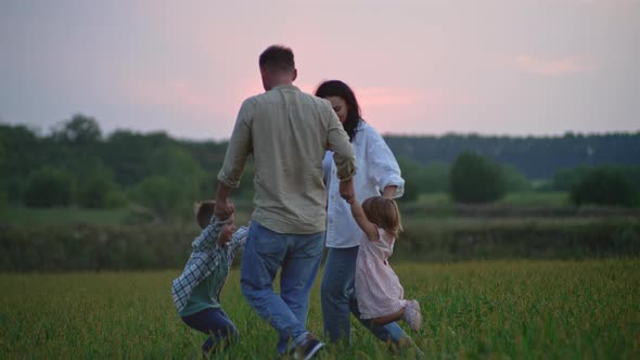 Family Holding Hands Dancing at Sunset in Nature