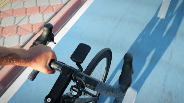 Man riding road bicycle along empty cycle path, POV shot