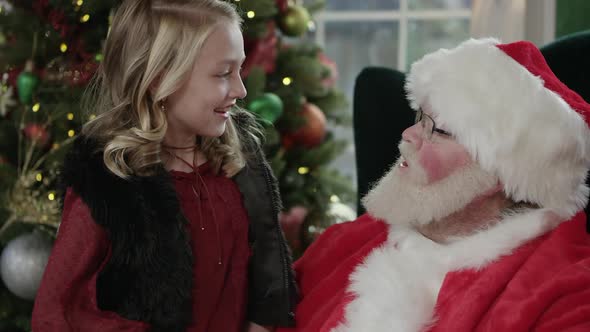 Young girl smiling as she sits on Santa's lap