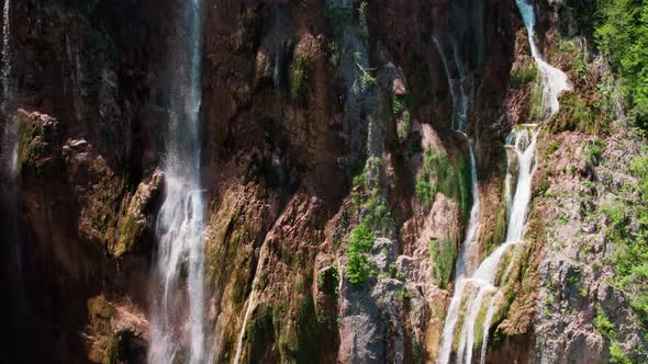 Drone slow motion ascent revealing Croatian village surrounded by waterfalls