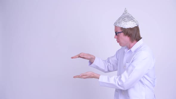 Young Man Doctor with Tinfoil Hat Shaking While Showing Something