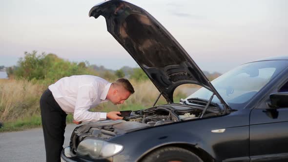Businessman with the problem of checking the car under the hood.
