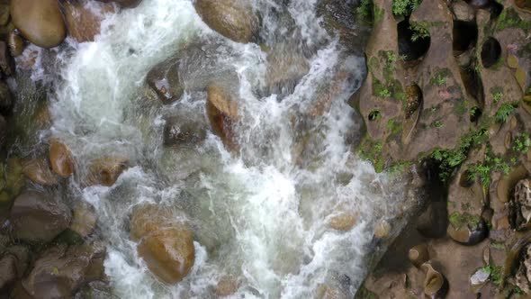Top view of a river with a fast current running alongside rocks
