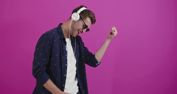 Man Dancing and Smiling Over Color Background While Listening to Music