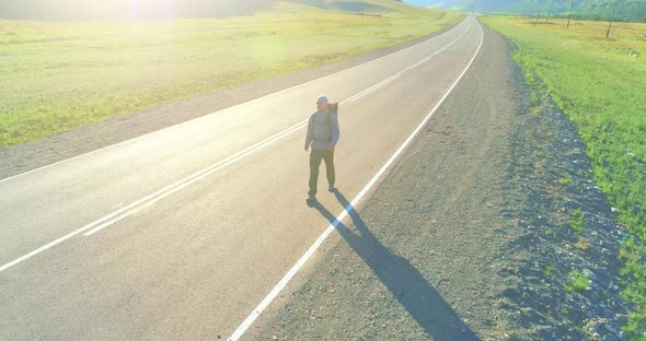 Flight Over Hitchhiker Tourist Walking on Asphalt Road