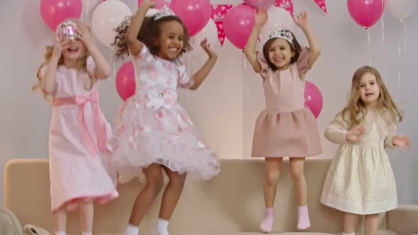 Little Girls Jumping and Waving on Sofa alt