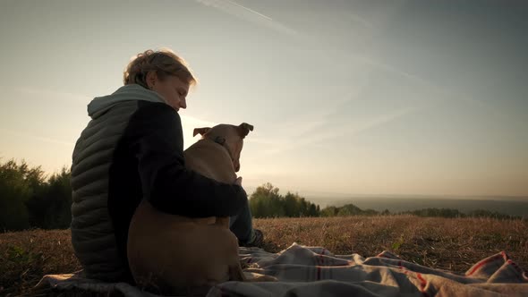 Silhouettes of Woman Sitting with a Dog During Amazing Sunset