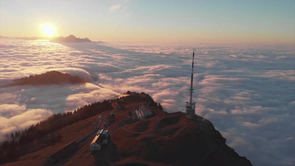 Sunset drone view to mountain top surrounded by a sea of clouds. Famous Rigi Mountain in Switzerland