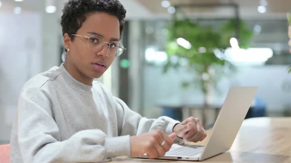Casual African Woman with Laptop Showing Thumbs Down