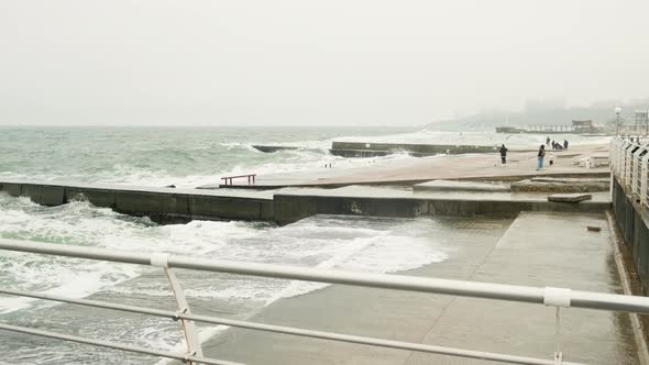 Storm in the Promenade Fenced with Concrete Breakwater in Cloudy Weather with a Leadgray Sky and