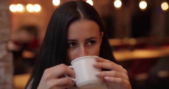 Woman with Enjoyment Drinking Coffee in Cafe