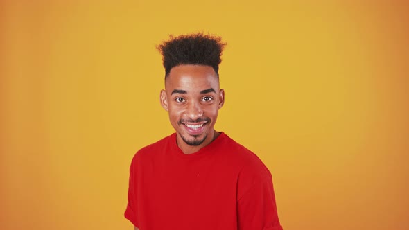 Cheerful Black Man Jumping Into Shot and Indicating Happily at Camera Orange Studio Background