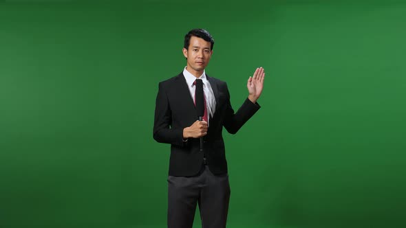 Asian Businessman Pointing On Something And Talking On A Green Screen, Chroma Key