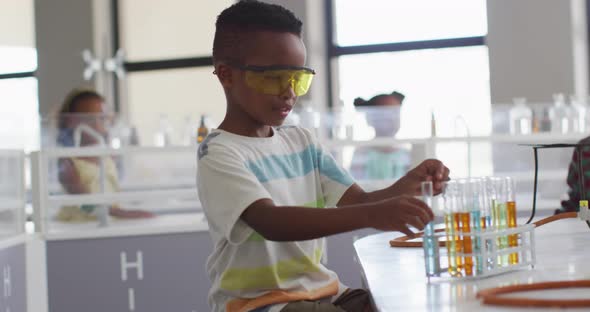 Video of happy african american boy wearing glasses during chemistry lesson