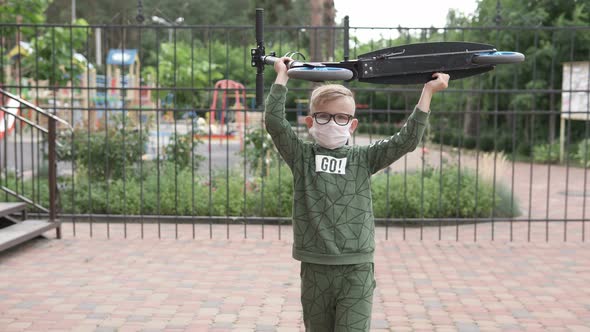 A boy carries a scooter over his head on the street during quarantine.