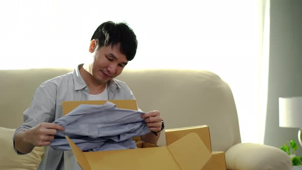happy man open cardboard parcel box in the living room at home, purchase on online store