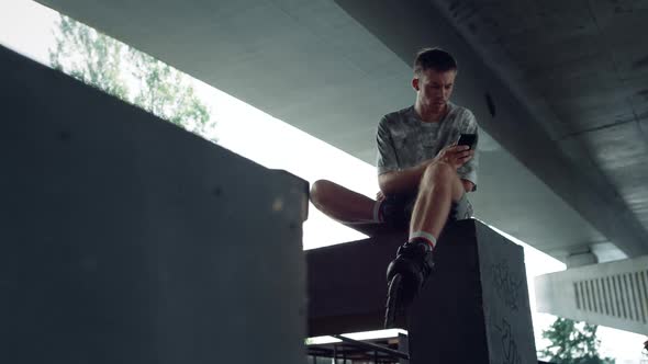 Relaxed Millennial Browsing Internet Online on Mobile Phone at Skatepark