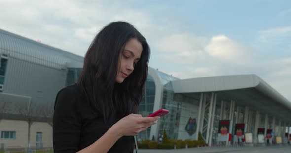 Beautiful Girl Is Smiling and Texting and She Standing Near the Airport